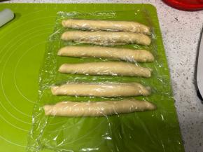 从长边卷起面团，每一份都如此卷好，盖上保鲜膜松弛10分钟