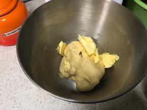 直到面团出筋，用手按上去不会粘手上，加入提前软化切片的黄油，继续4档揉面，大约15分钟