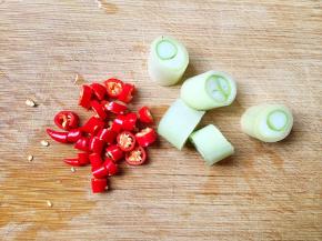 将小红尖椒和葱切段。