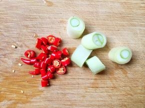 将小红尖椒和葱切段。