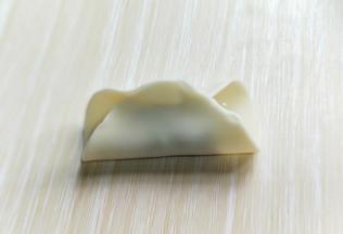 将饺子皮对折，如图。