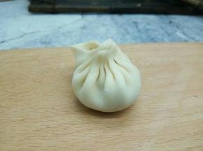 左手的食指把旁边的面皮推向右手食指的位置，形成一个褶子的形状，捏完最后一个褶，