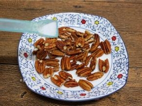 碧根果撒上一点点盐粉，均匀摊开；