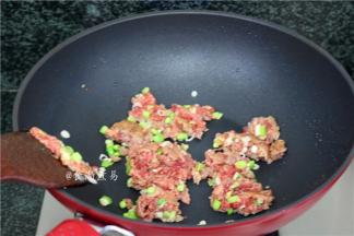 煸好的豆腐盛起，接着将葱头和牛肉煸炒片刻