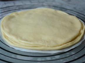 取另一个面团压扁擀成一张大圆面皮，重叠在涂抹果酱的面皮上，涂抹上适量的果酱，就这样重复步骤做好剩下的面皮，重叠在一起。