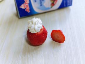 再用裱花袋把奶油挤到草莓下半部切口部分，如图。
再把切掉的三分之一部分做圣诞老人的帽子。