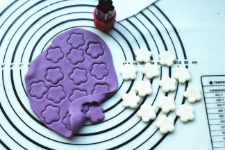 分别取一份紫色和白色面团，擀成片，用工具刻出白色和紫色的花朵，待用。