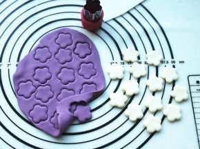 分别取一份紫色和白色面团，擀成片，用工具刻出白色和紫色的花朵，待用。