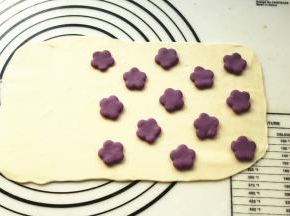 四份面团分别擀成厚片。在其中一片白色面片上放紫色花朵，一片紫色面片上放白色花朵。
这个是白底紫花。