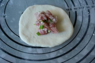 7.取一白色面团擀圆，放入适量的内馅儿。