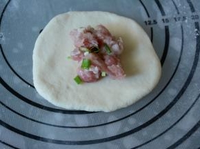 7.取一白色面团擀圆，放入适量的内馅儿。