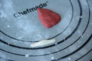 9.取一小块红色面团捏成圣诞帽子的形状（大致三角形），再取一小部分白色面团做成宽长条作为圣诞帽的边缘。