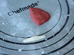 9.取一小块红色面团捏成圣诞帽子的形状（大致三角形），再取一小部分白色面团做成宽长条作为圣诞帽的边缘。