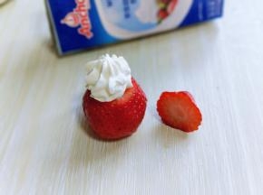 草莓洗干净后捞出淋干水份，将顶部的三分之一切下来。再用裱花袋把奶油挤到草莓下半部切口部分，如图。 再把切掉的三分之一部分做圣诞老人的帽子。再用熟黑芝麻，做圣诞老人的眼睛和鼻子。再给圣诞老人戴顶帽子，挤上一点打发的淡奶油即可哈！