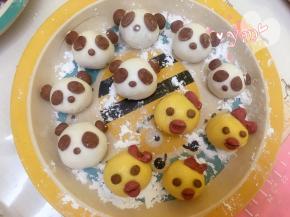 小鸡面团：取一点南瓜面团搓圆按扁，包入黑芝麻馅，捏紧收口，揉圆即可。取可可面团搓一个小圆做眼睛，取红曲面团做蝴蝶头饰和嘴巴，用筷子压下即可。