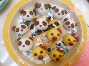 小鸡面团：取一点南瓜面团搓圆按扁，包入黑芝麻馅，捏紧收口，揉圆即可。取可可面团搓一个小圆做眼睛，取红曲面团做蝴蝶头饰和嘴巴，用筷子压下即可。