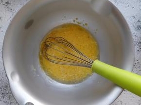 在蛋黄盆中，加入植物油和牛奶，用手动打蛋器朝一个方向搅动。