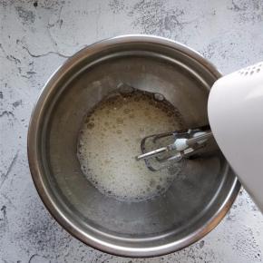 用电动打蛋器朝一个方向打发蛋清，形成鱼眼泡时，加入一半量的细砂糖打发。