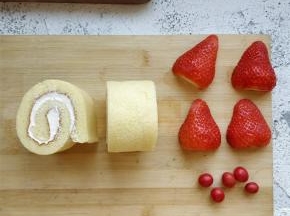 将草莓去蒂，纵向切成两半，根据每块草莓的宽度，将蛋糕卷切成相应宽度的块儿。