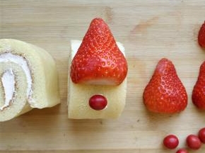 把切好的草莓和巧克力豆，在恰当的位置粘好，充当圣诞帽和红鼻头。