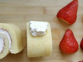 在蛋糕卷中线偏上的位置，挤少许奶油，起到粘合草莓和蛋糕体的作用。