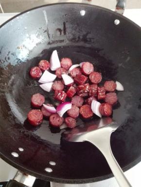 炒锅里放适量的油，放入洋葱炒出香味，放入腊肠煸炒至出油