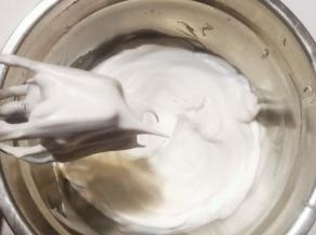 蛋清分次加入剩下的白糖，打发至接近干性发泡状态；