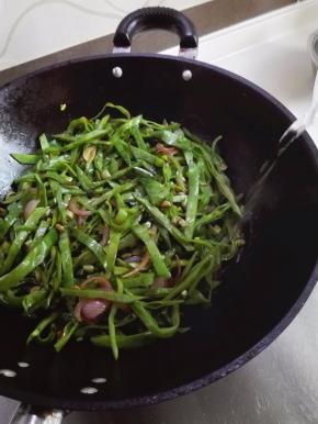 扁豆的水分极少，需要顺着锅边淋入少许的清水以免糊锅，翻炒至水分蒸发掉，再次淋入少许的清水