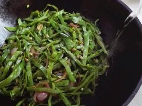 扁豆的水分极少，需要顺着锅边淋入少许的清水以免糊锅，翻炒至水分蒸发掉，再次淋入少许的清水