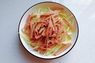 火腿与土豆丝放入盘子中，调入少许盐、鸡精和食用油拌均匀；