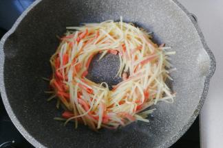 然后把火腿土豆丝用锅铲拨成一个圆圈形；