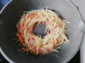 然后把火腿土豆丝用锅铲拨成一个圆圈形；