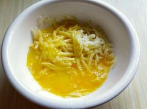 将打散的蛋液倒入剥好的土豆丝器具中。