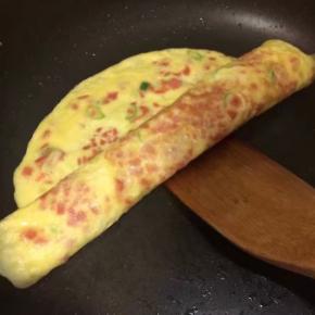 一定用小火慢煎至9.5分熟，用锅铲慢慢从一边卷向另一边