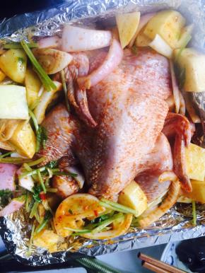 把蔬菜放在烤盘底部，把鸡放在上面，用毛刷在鸡皮上刷油