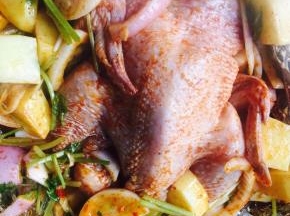 把蔬菜放在烤盘底部，把鸡放在上面，用毛刷在鸡皮上刷油