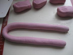 取出面团至案板上，使劲揉面，揉至光滑无气孔；取一块面团搓成长条