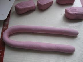 取出面团至案板上，使劲揉面，揉至光滑无气孔；取一块面团搓成长条