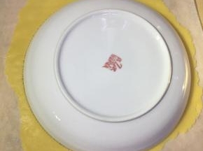 拆一张和烤盘一样大的油纸。醒好面后，取一个面团放油纸上，轻轻擀平，然后找一个八寸盘子（一般情况下家里日常用的盛菜盘子都是八寸的）扣在上面，然后用牙签绕盘子周边画一圈。取下盘子