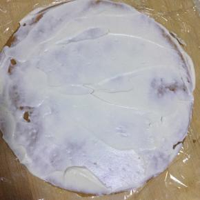 案板或者裱花台上铺一张保鲜膜，大一点拆。然后准备第一张饼铺好，抹一层淡奶油