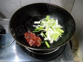 香肠拨一边，倒入大蒜梗，炒匀。