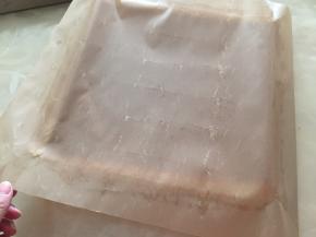 出炉倒扣烤网上，将四边油布扯开散去热气，待温热扯掉油布，拿一张油纸放在蛋糕上面，倒扣回来