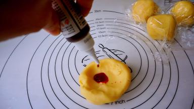 取其中一块，滴入红色素，用叠拌的手法使之均匀