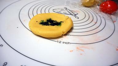 再取一块面团，滴入绿色素，同样叠拌均匀