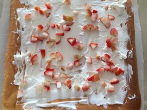 将一部分奶油铺在蛋糕上，撒上切好的草莓