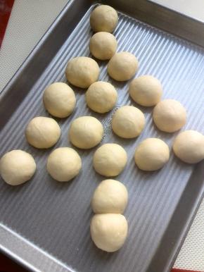 醒发结束，再次将面团滚圆，滚圆后的面团按圣诞树的形状放入烤盘里；树干我用2个小面团紧挨在一起