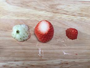 草莓洗净吸干水分切掉底部，再从三分之一处切顶部，如图；