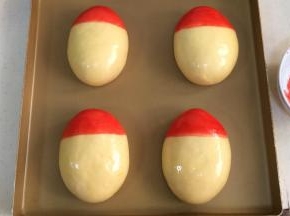 然后取少许红色色素，刷在面团的一头，做帽子部分。（我这里用的是液体的色素，非液体的可以滴几滴水化开后刷）