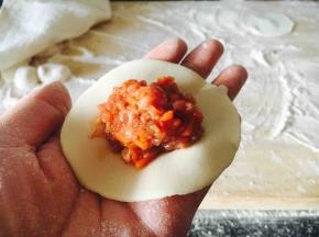 往饺子皮上放适量的饺子馅。