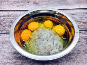 把鸡蛋磕入盛有鲜虾皮的容器里。